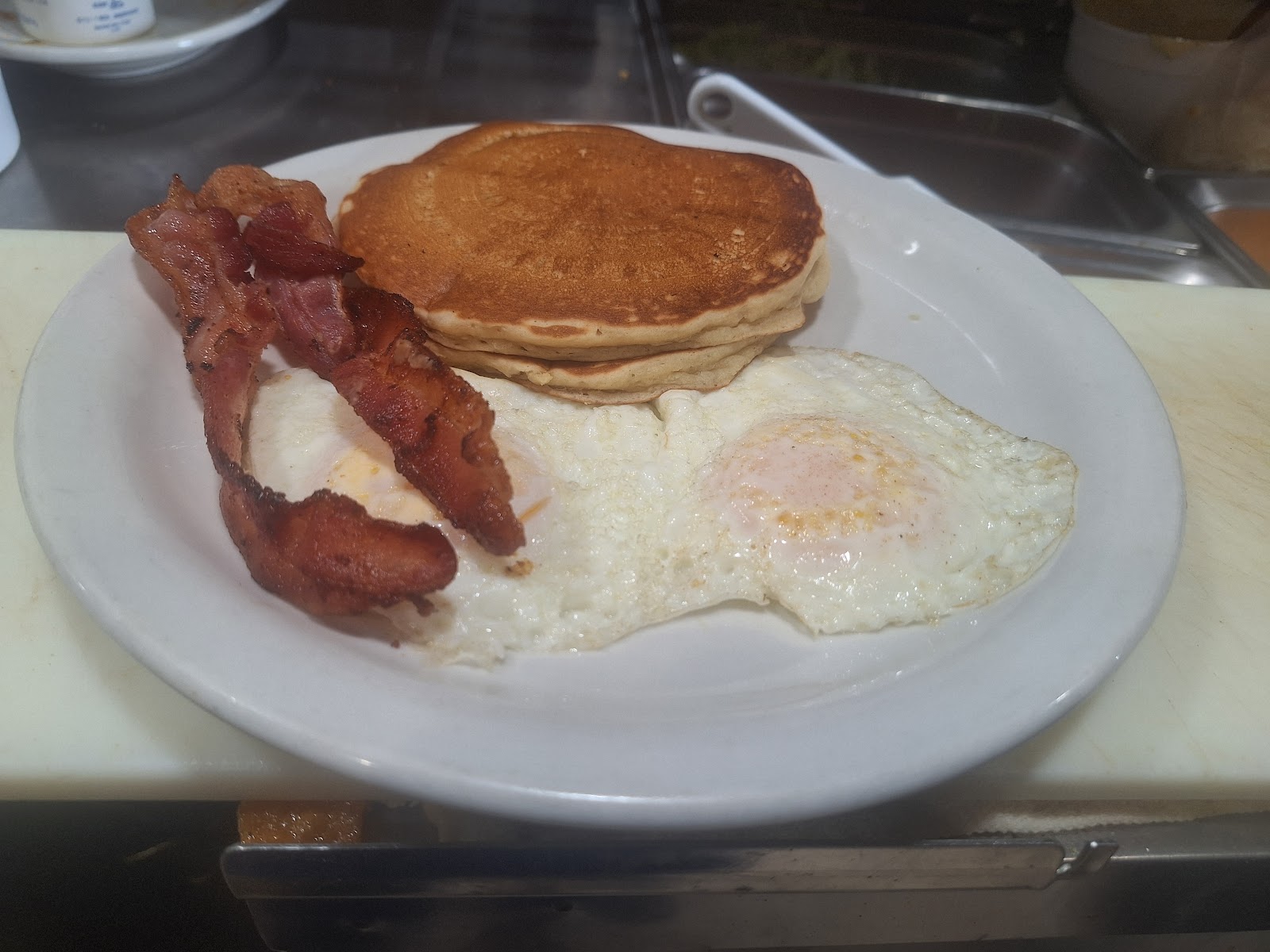 Pancakes, fried eggs, and bacon breakfast plate